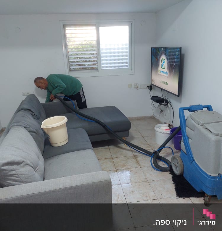 אדם מנקה ספה עם מכונת ניקוי מקצועית